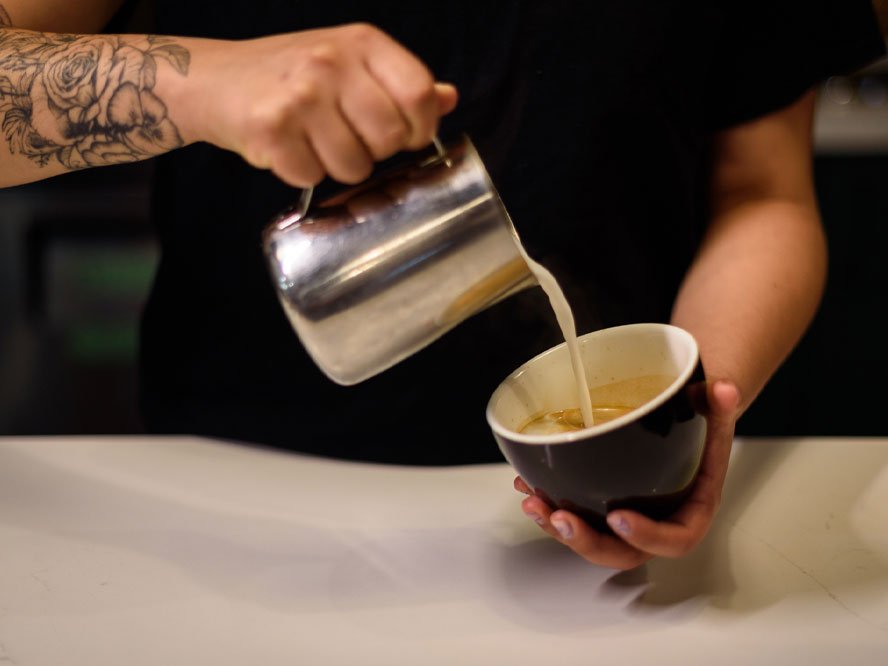 Barista pouring coffee to create latte art at The Rosemount Café, a coffee shop in Toronto.