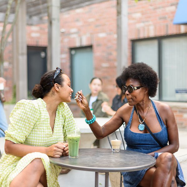 Mother and daughter seated on the patio of a Toronto coffee shop, enjoying matcha coffee and cafe crema.