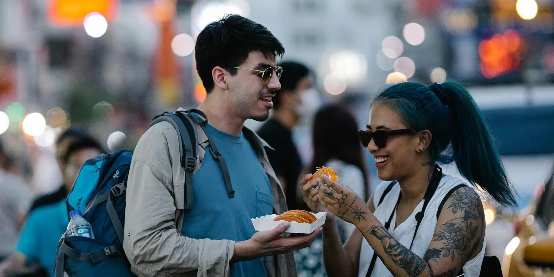 Two tourists enjoying tacos at a food market in Toronto.