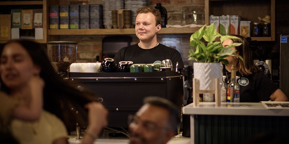 Barista standing behind the counter of a cafe and bakery in Weston village - The Rosemount Cafe.